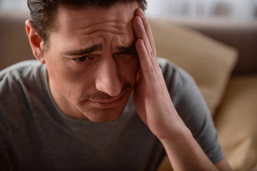 Man rubs his forehead while wondering, "is Xanax a benzo?"